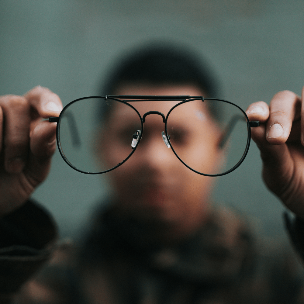 blurry image of a man holding up glasses 