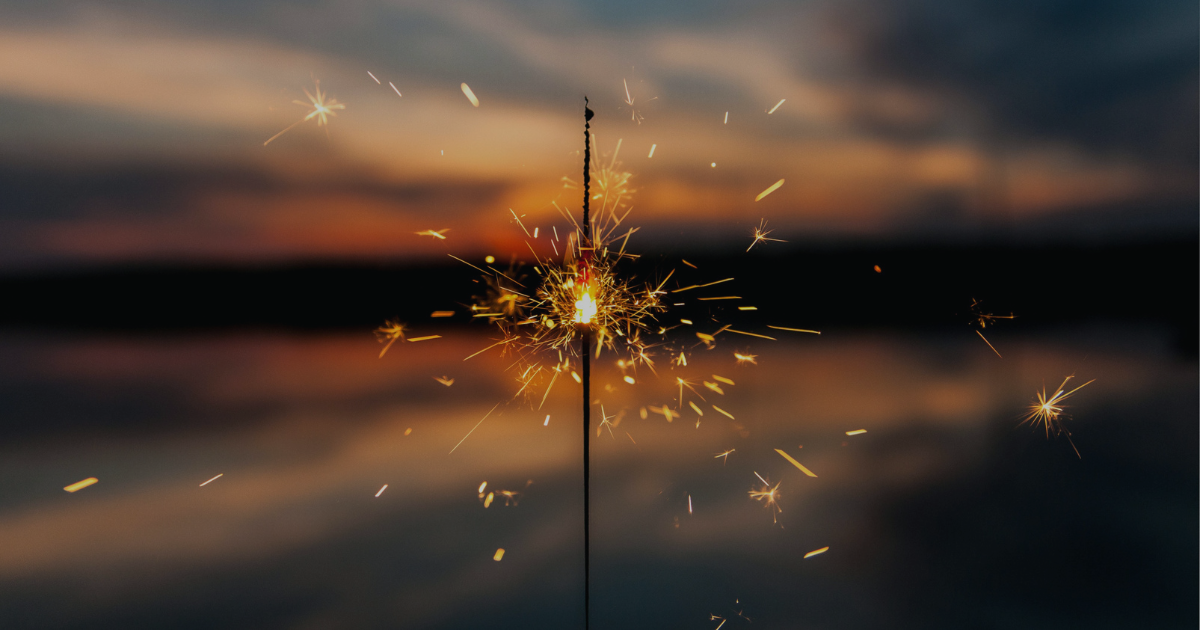 A sparkler firework in front of a sunset 